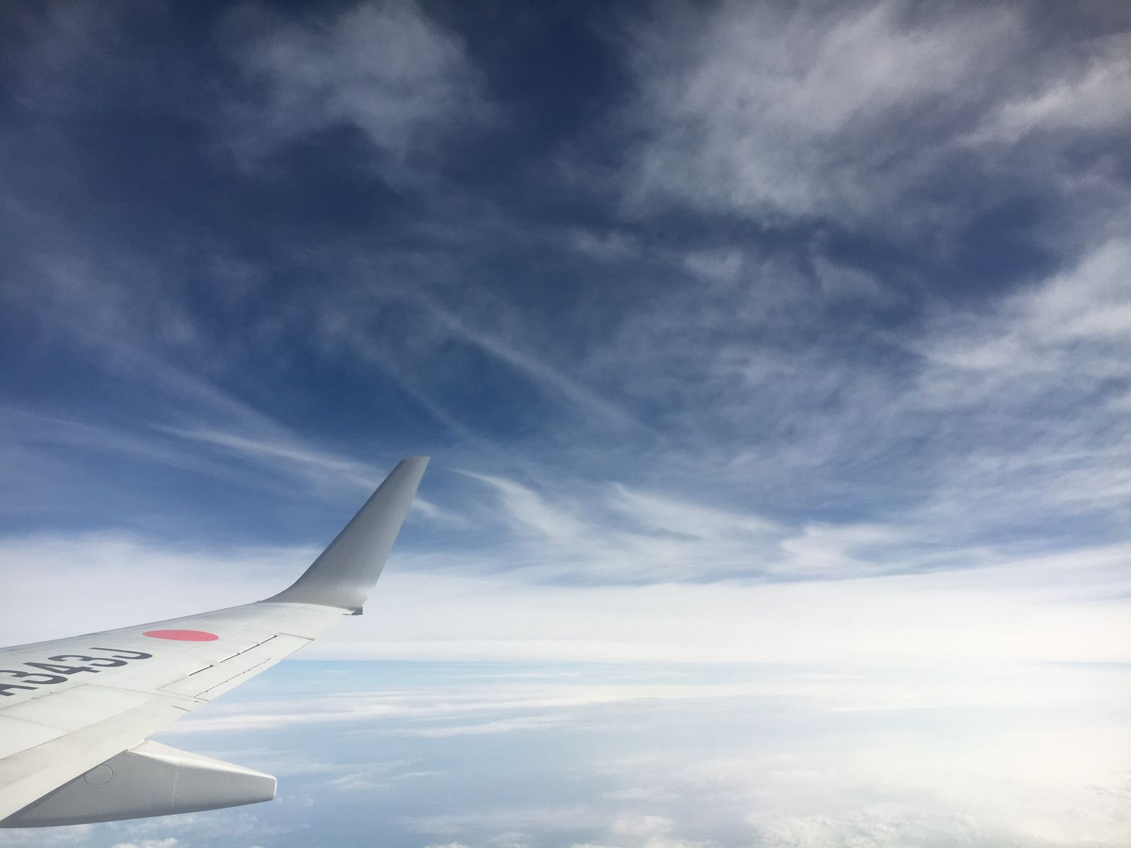 View along an airliner's wing above a layer of cloud