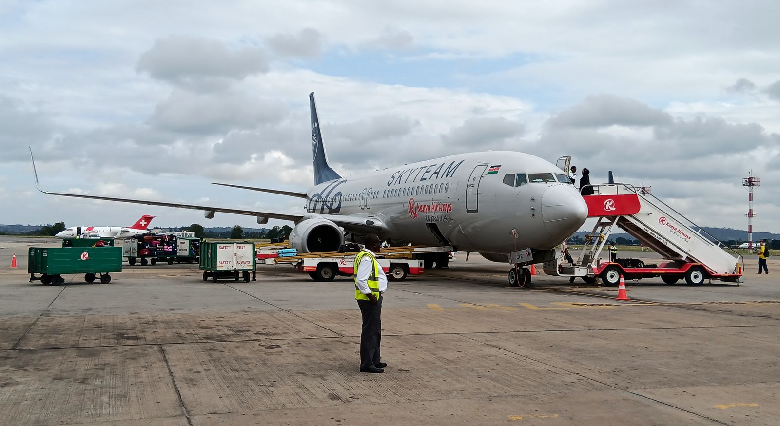 Passengers boarding a Kenya Airways Boeing 737 by airstairs on the apron